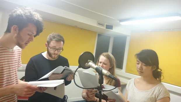 Four young Actors rehearse dialogue from a radio play performance in The Out of the Blue Drill Hall's Music Room.