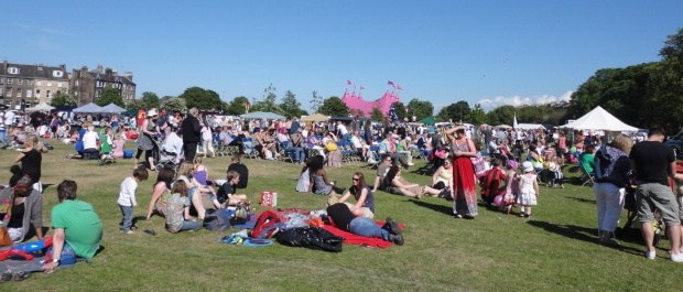 People sit in the sun while Leith Gala Day happens in Leith Links