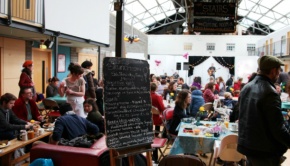 The Drill Hall Arts Cafe Bruncheon lunch menu surrounded by a busy crowd while a guitarist plays in the background