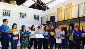 A large choir passionately sings in the main space of the Drill Hall
