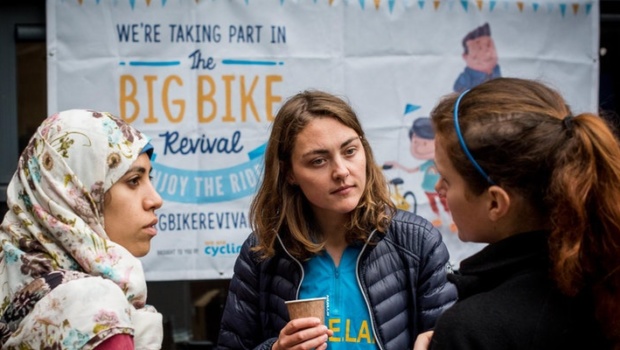 Three women talking about cycling in front of a 'Big Bike Revival' poster.