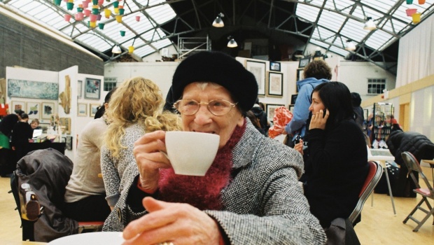 Woman sitting at a table in the Drill Hall cafe enjoying a cup of tea